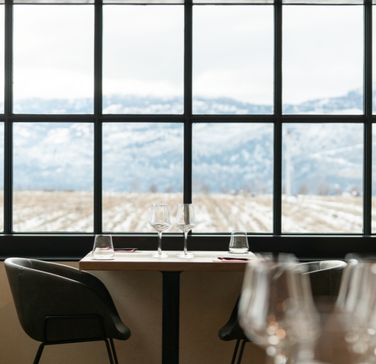 Indoor wine tasting seating looking out over snowy vineyards.
